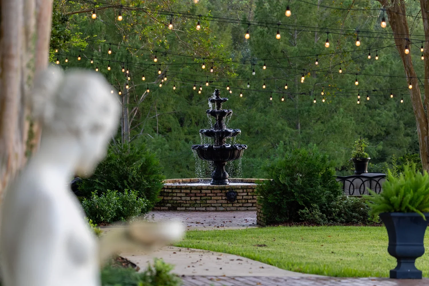 A garden statue, fountain, and trees in the Overlook Courtyard.