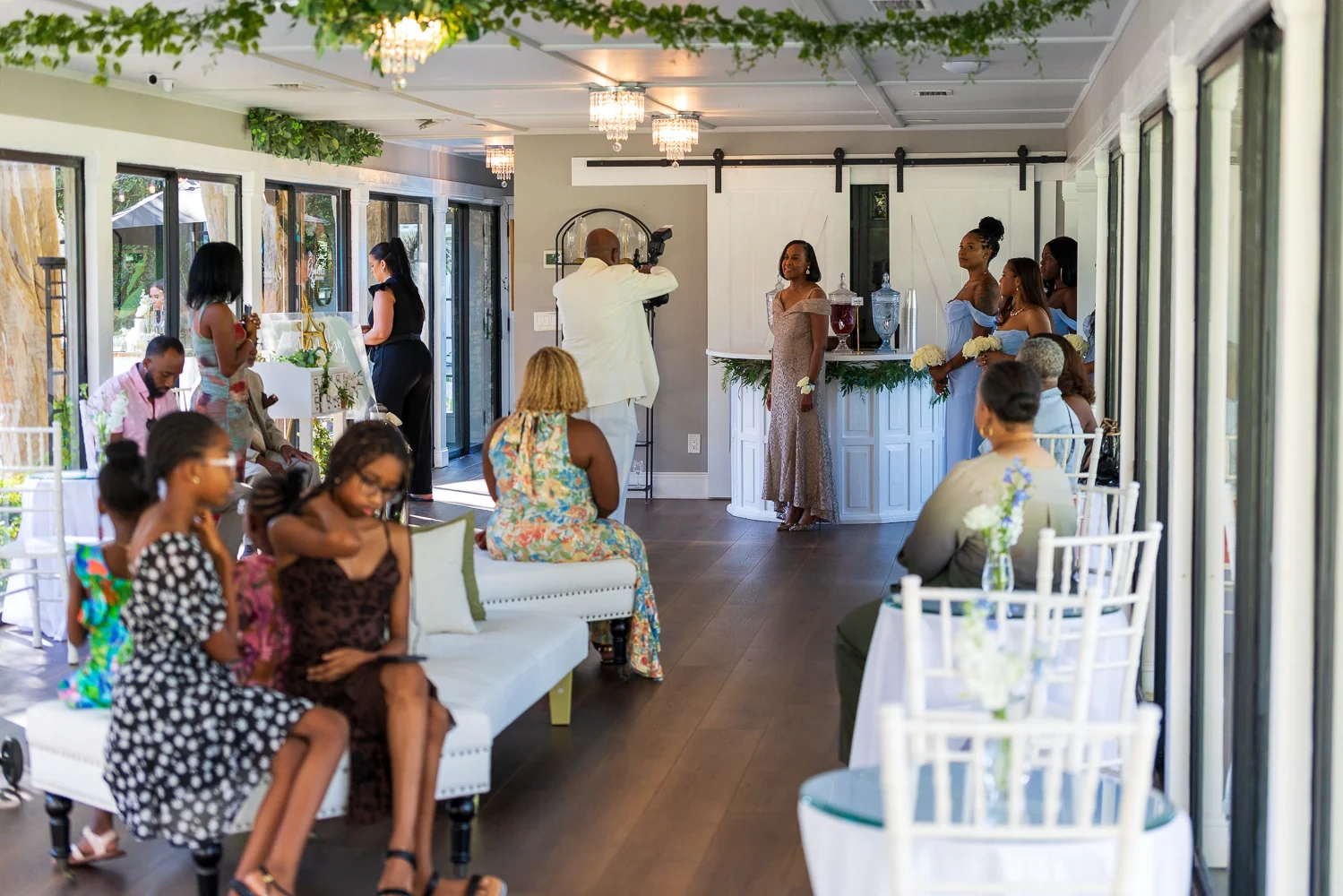 Guests seated and standing around the Glass Hall’s lounge and bar, with the courtyard visible through the open doors.