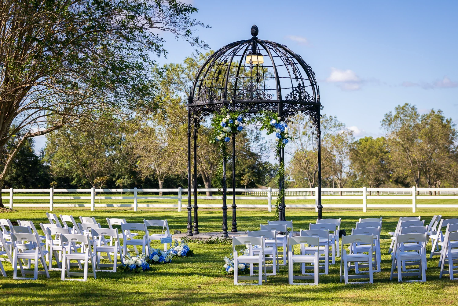 An illuminated iron garden rotunda against the evening sky.